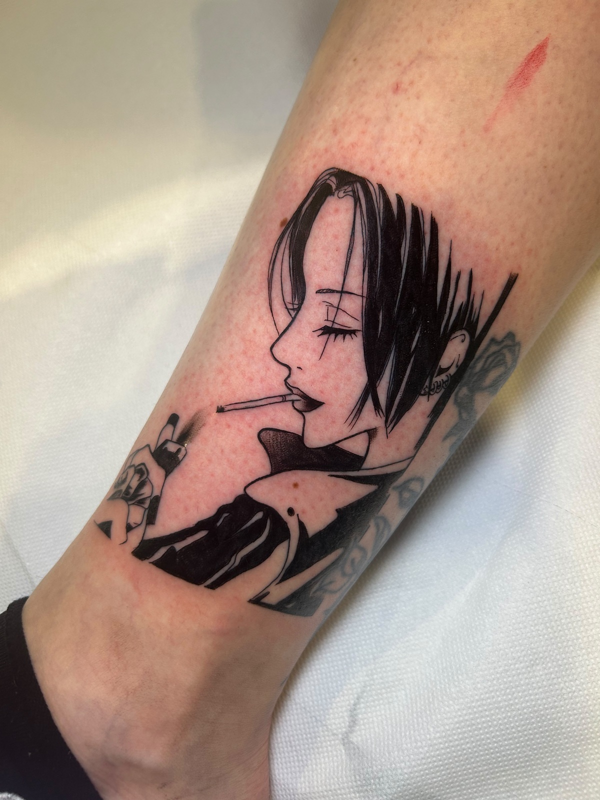 Tatuaggio di Nana in bianco e nero, sul lato della gamba